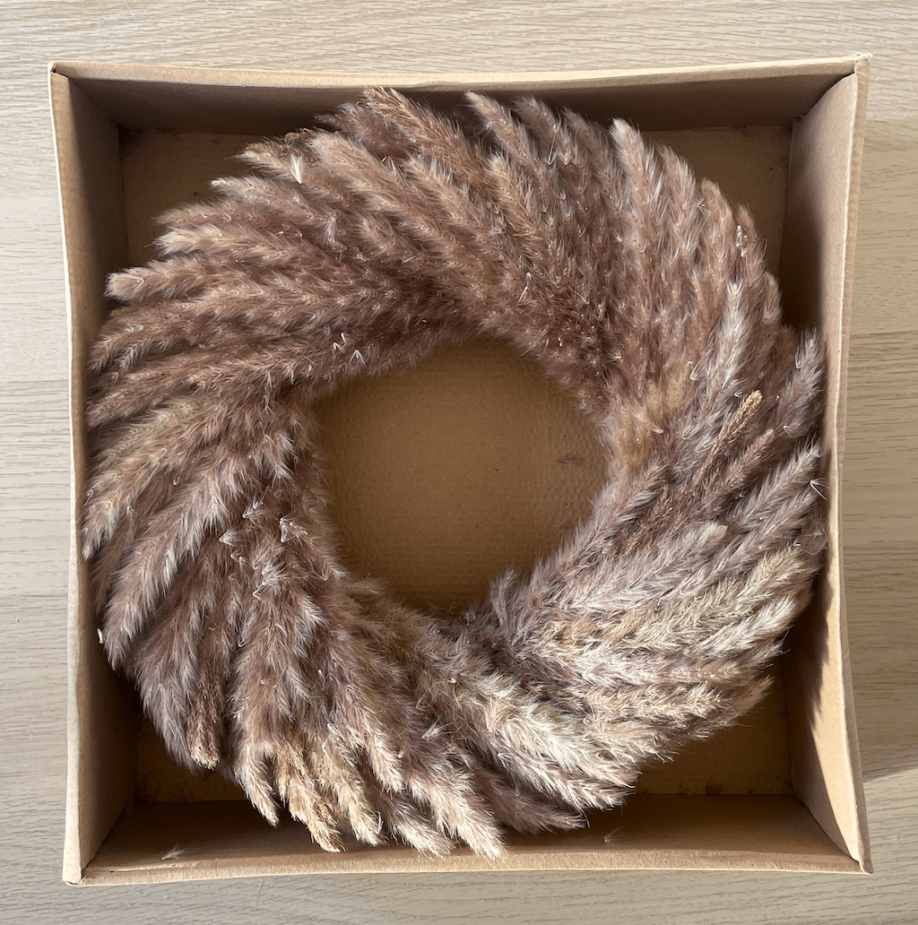 Pampas Grass Wreath in a cardboard box on a wooden surface