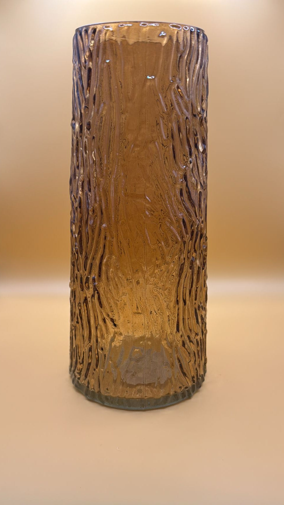 Cylindrical ceramic vase with textured surface on a beige background