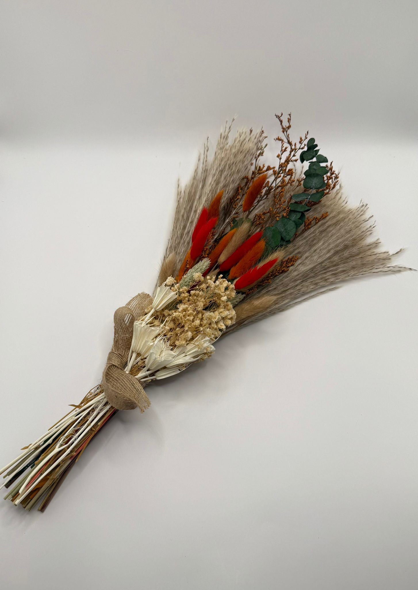 Bouquet of dried flowers with red and green accents on a white background