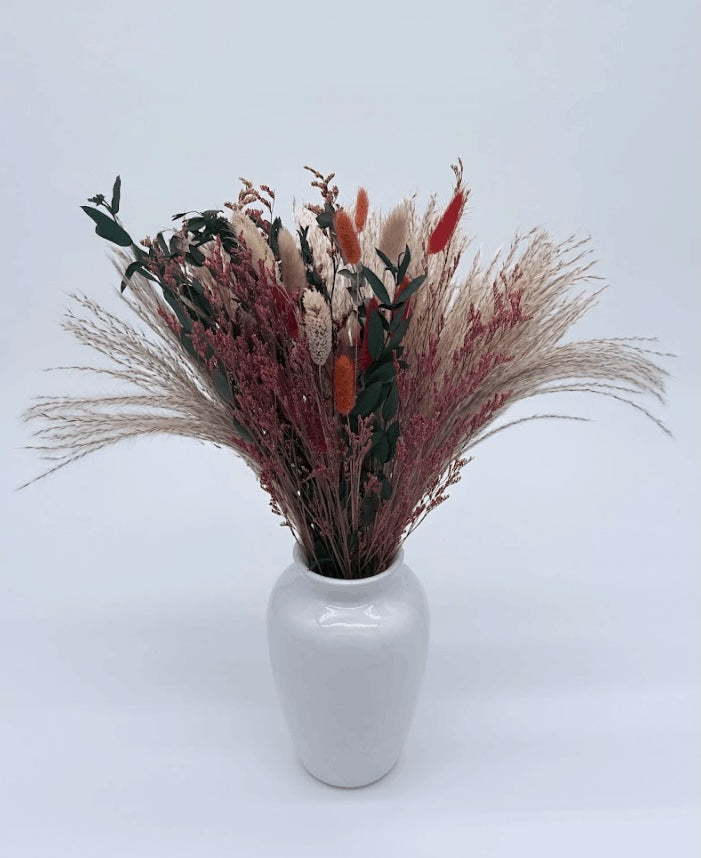 Bouquet of dried flowers with red and green accents on a white background