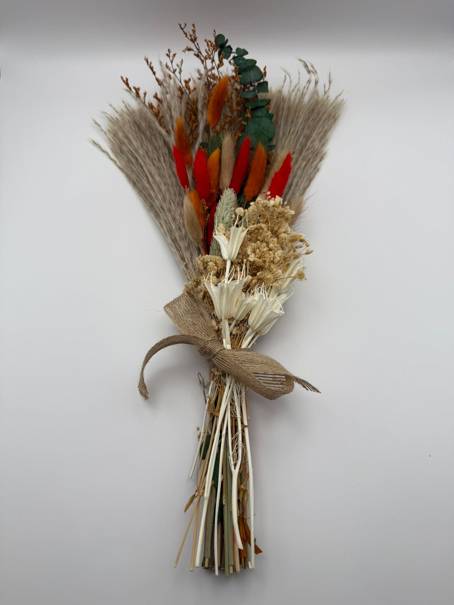 Bouquet of dried flowers and leaves tied with burlap on a white background