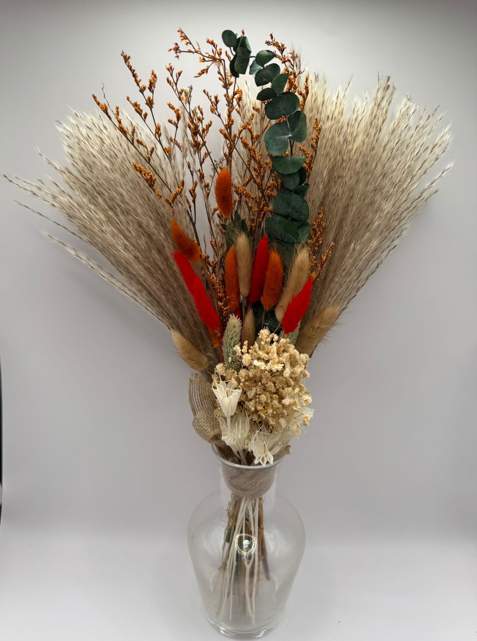 Bouquet of dried flowers in a clear vase on a white background