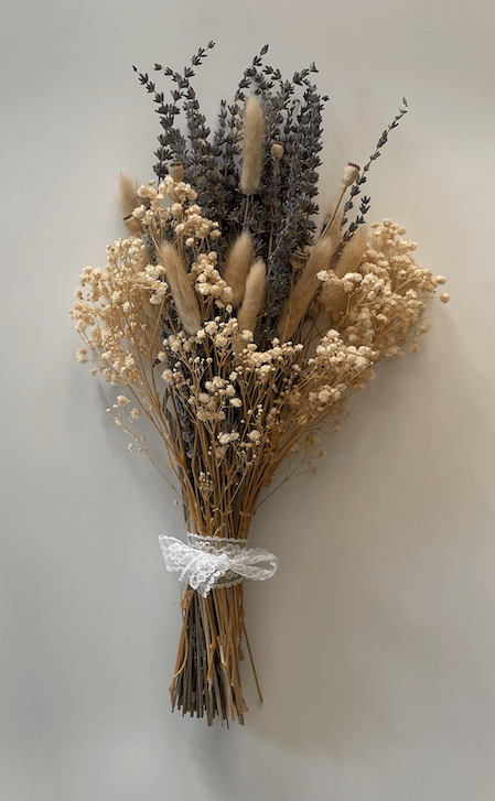 Bouquet of dried flowers tied with a white ribbon on a light background