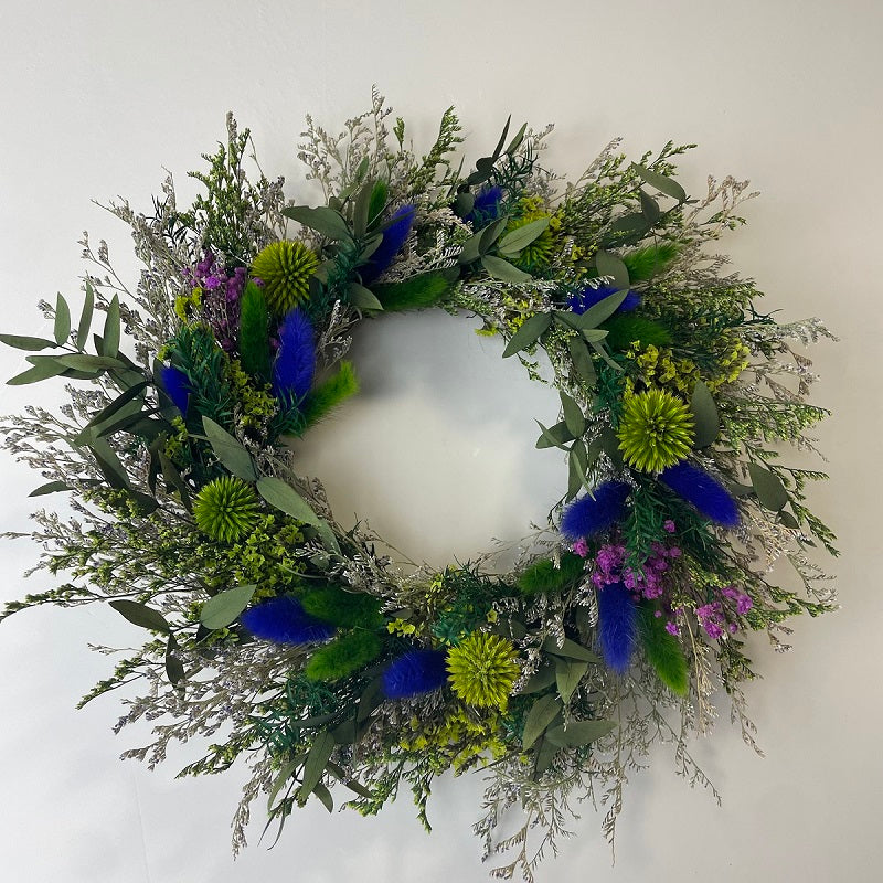 Wreath made of bright blue, green and pale silver dried herbs and blooms