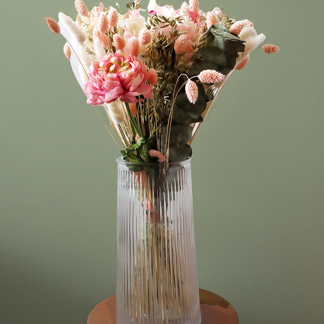 Clear glass vase with a bouquet of pink and white flowers on a green background