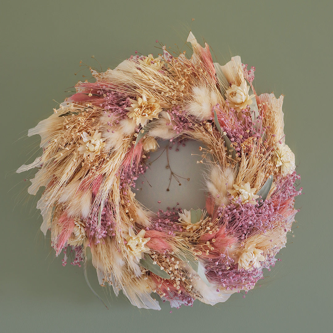 Decorative wreath with dried flowers and herbs on a green background