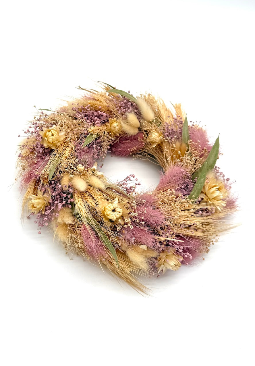 Decorative wreath with dried flowers and grasses on a white background