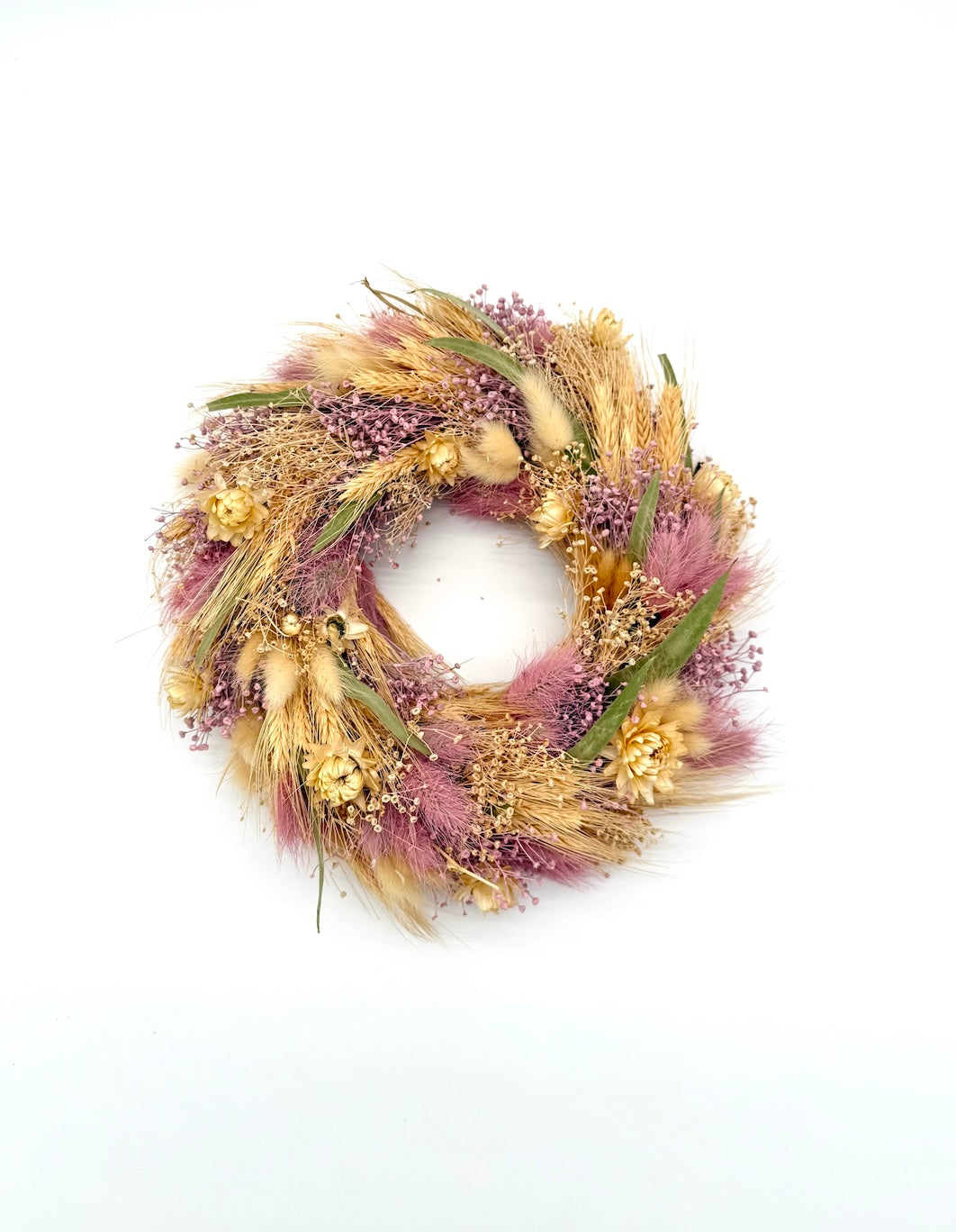Decorative wreath with dried flowers and grasses on a white background