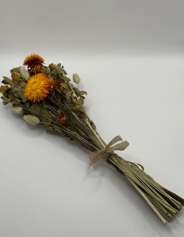 Bouquet of dried flowers with an orange bloom tied with brown twine on a white background