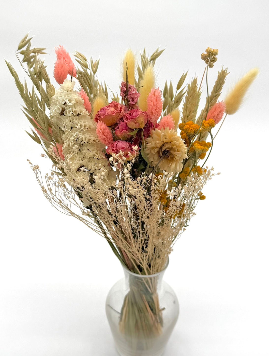 Bouquet of dried flowers in a clear vase on a white background