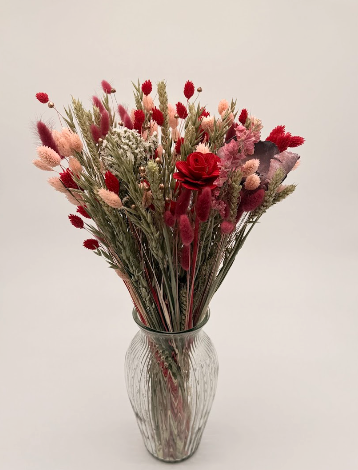 Bouquet of red and pink flowers in a ribbed glass vase