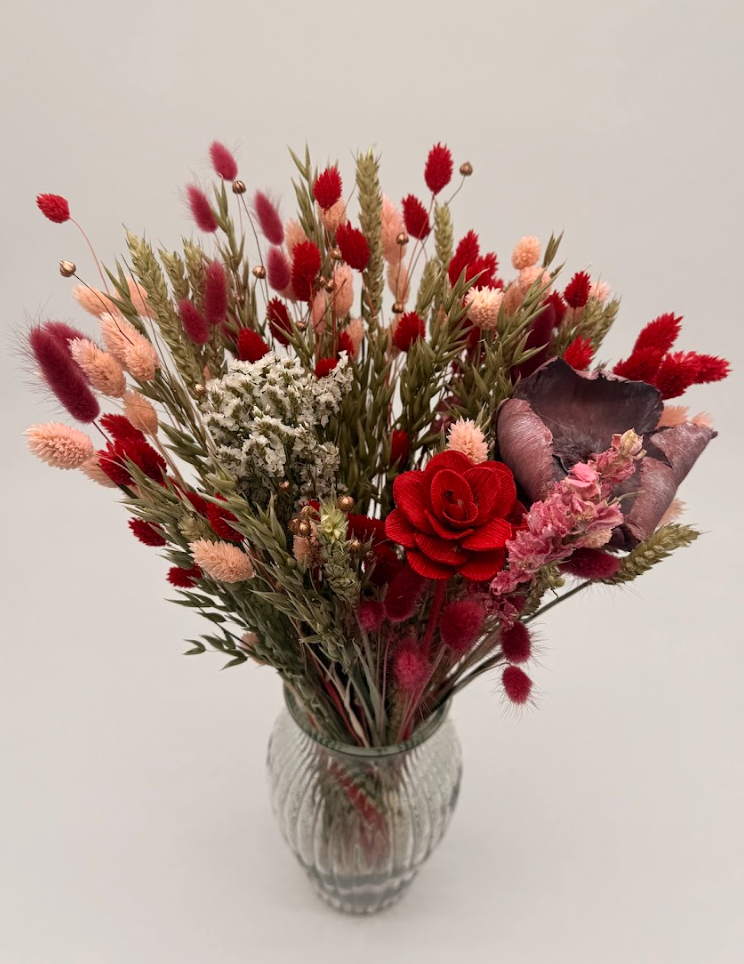 Bouquet of red and pink flowers in a ribbed glass vase