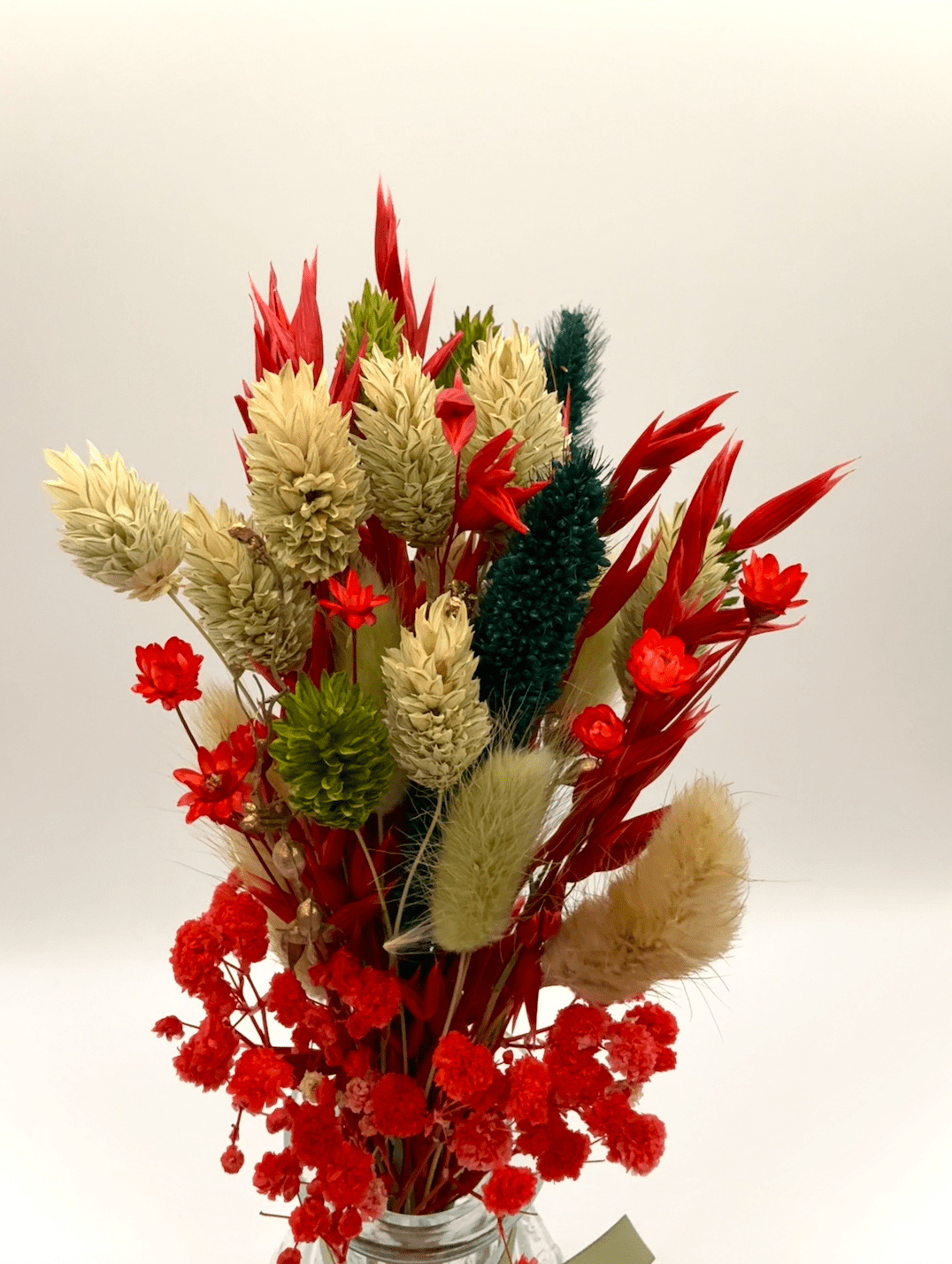 Bouquet of dried flowers in a clear vase on a white background