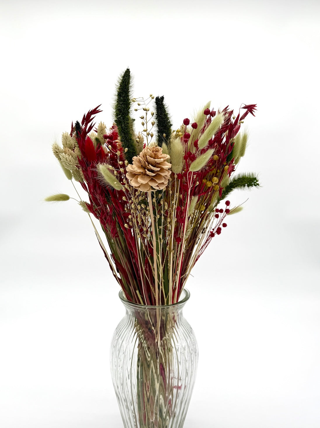 Bouquet of dried flowers in a clear vase on a white background