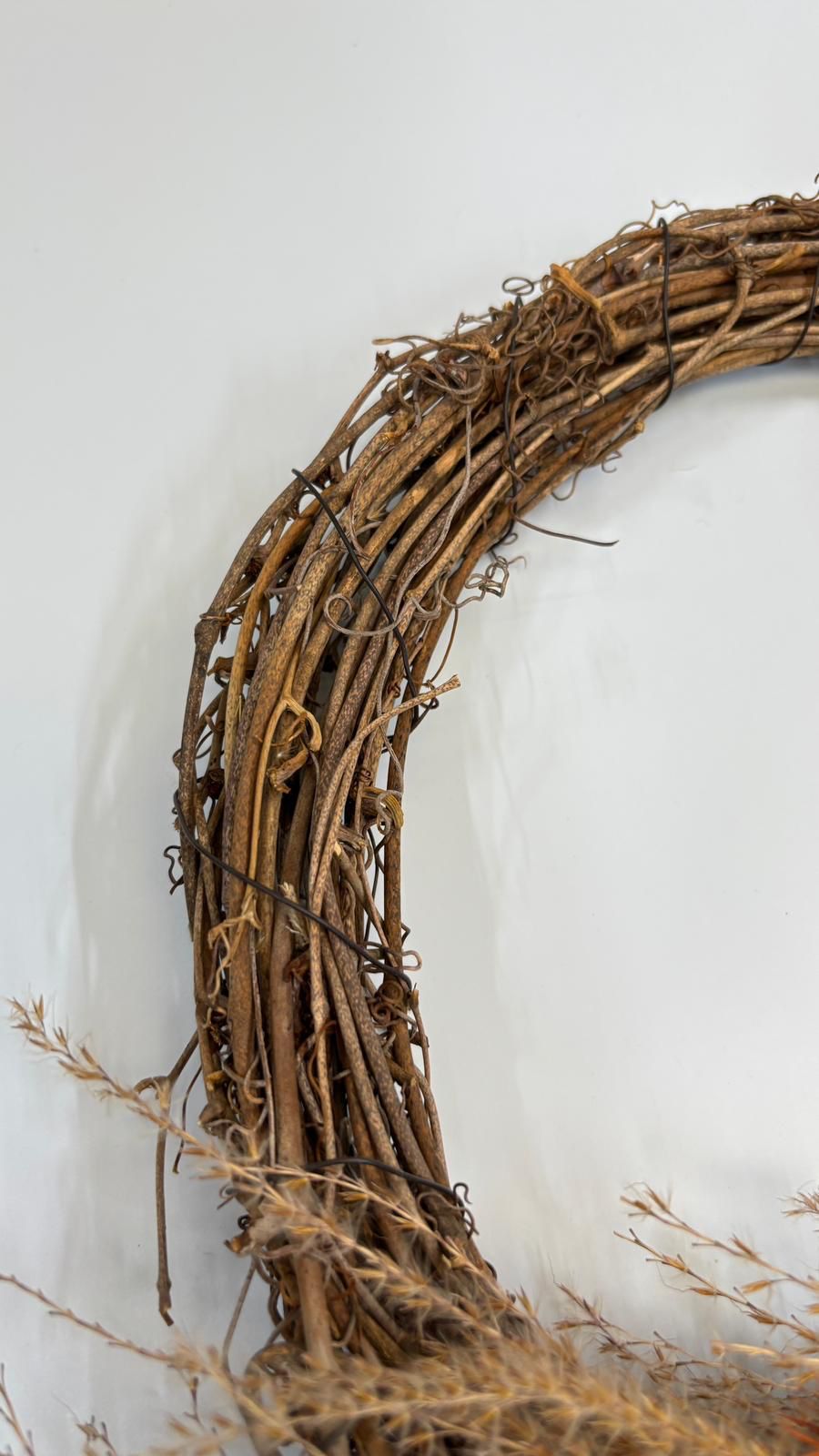 Close-up of a rustic grapevine wreath on a white background