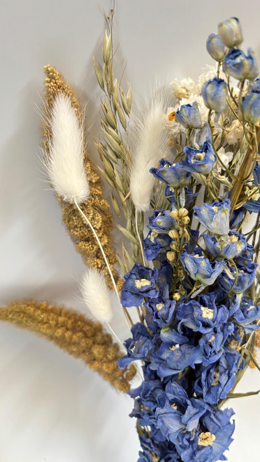 Decorative headband with dried blue flowers and gold leaves on a light background