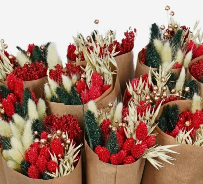 Bouquets of red and green flowers in brown paper cones on a white background