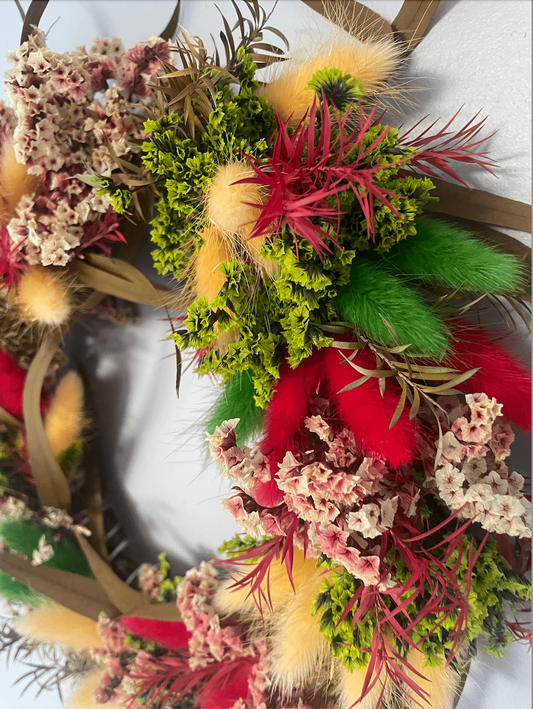 Decorative wreath with dried flowers and greenery on a white background