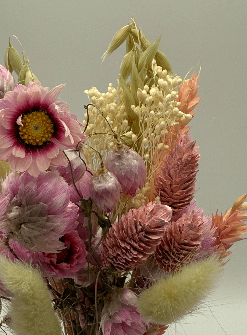 Bouquet of dried flowers with pink, yellow, and green colors on a light background