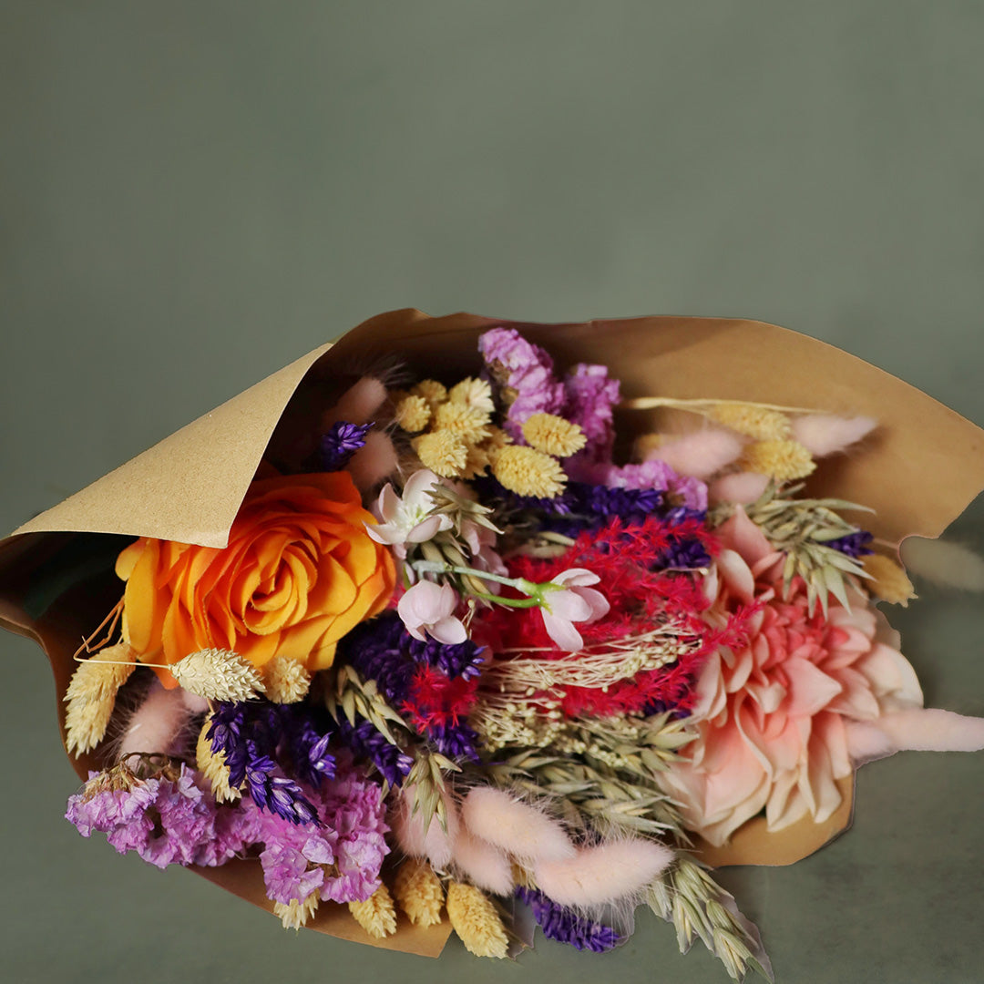 Bouquet of colorful flowers wrapped in brown paper on a gray background