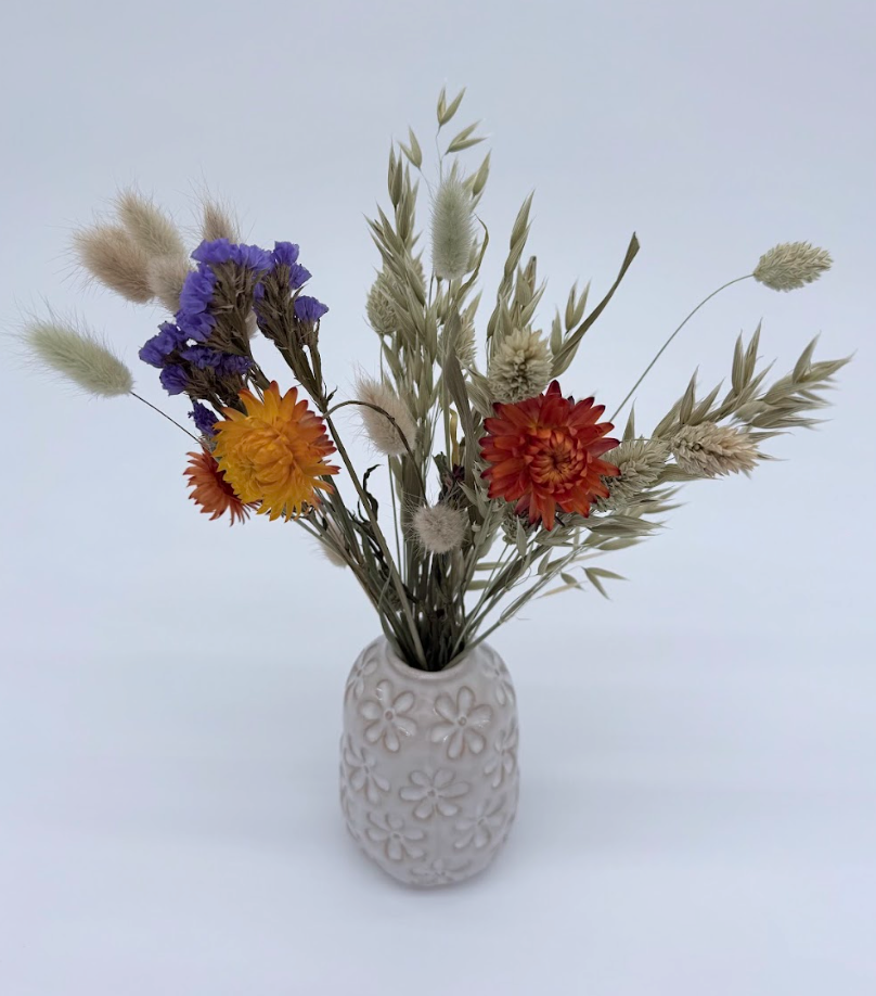 Decorative vase with dried flowers on a light gray background