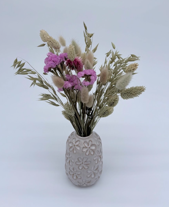 Decorative vase with pink flowers and greenery on a light gray background