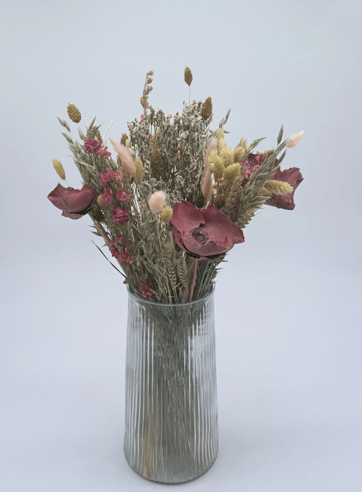 Dried Flower Bouquet with pink flowers and mixed stems in a ribbed glass vase
