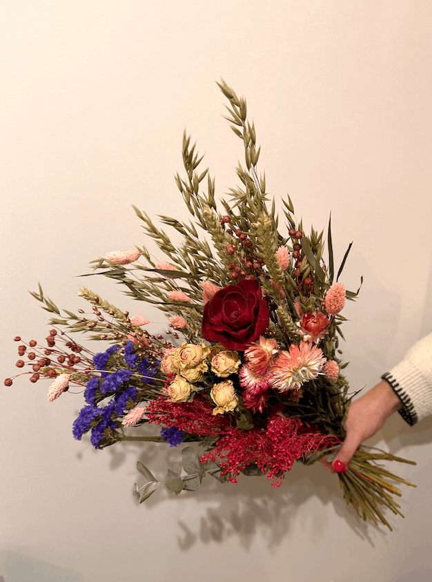 Bouquet of flowers held by a person against a plain background