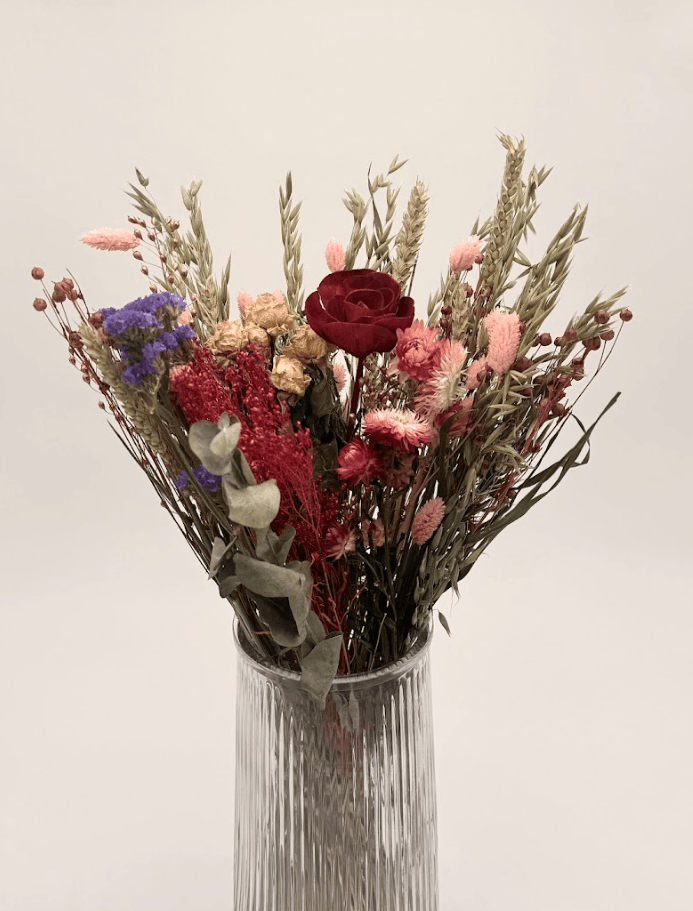 Bouquet of colorful flowers with a red rose in a ribbed glass vase