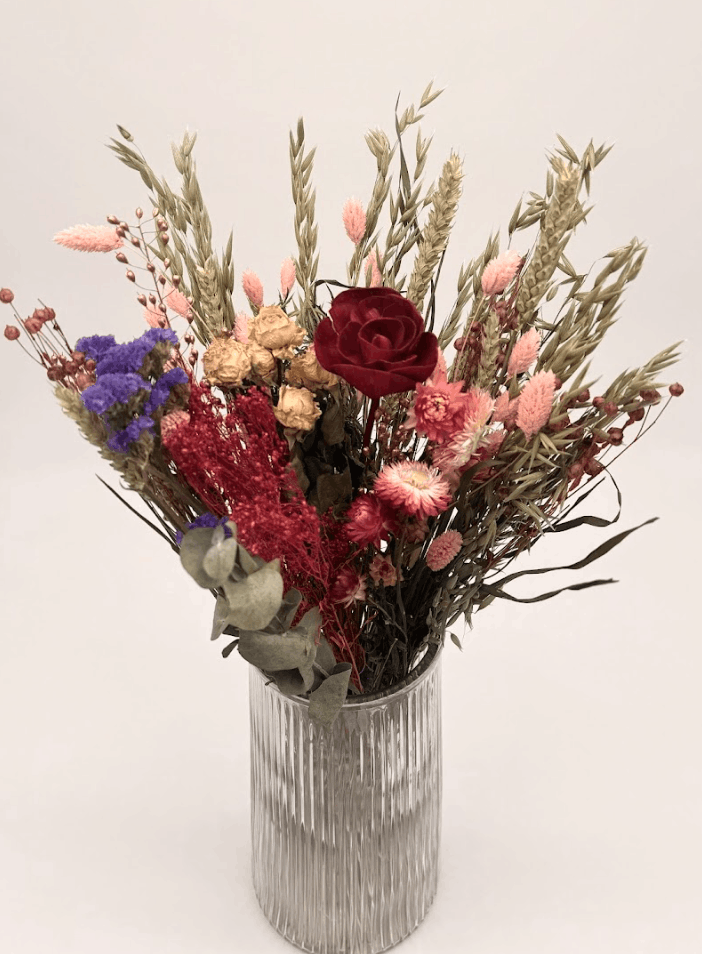 Bouquet of colorful flowers with a red rose in a ribbed glass vase