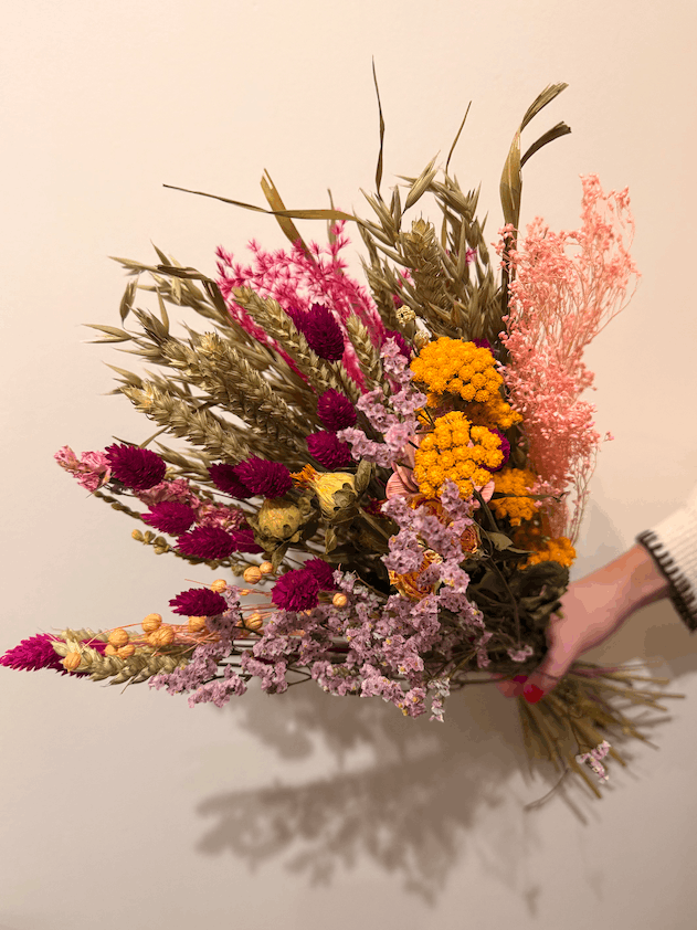 Bouquet of dried flowers held by a person against a neutral background