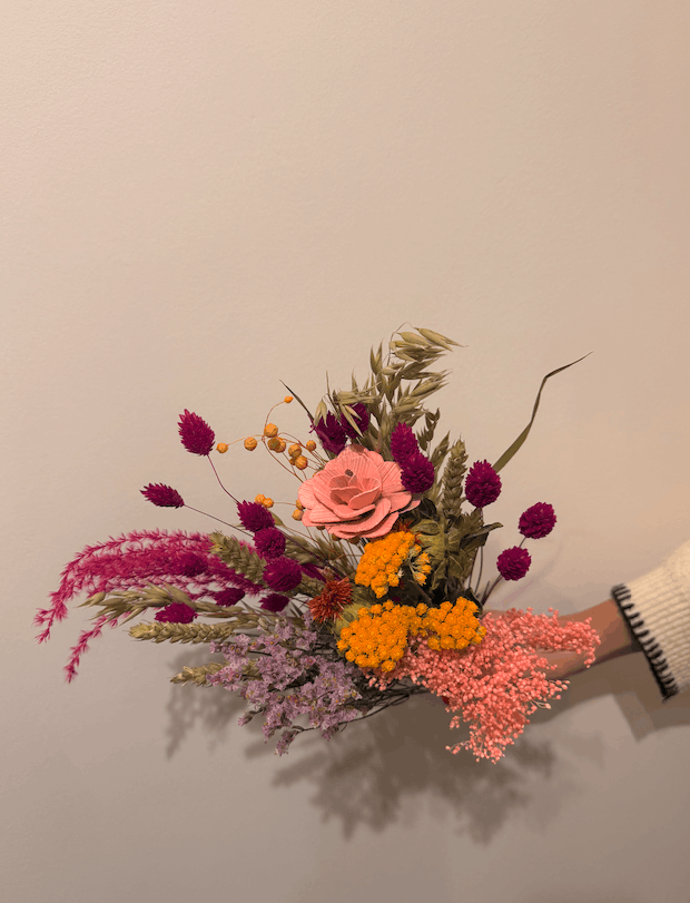 Bouquet of colorful flowers held against a plain background