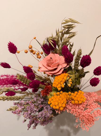 Colorful bouquet of dried flowers with pink, orange, and purple flowers on a neutral background