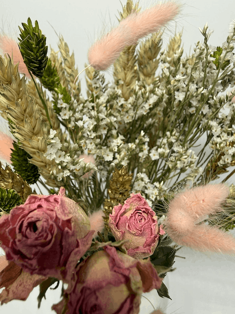 Close-up of dried flower bouquet with pink roses, white dried flowers, wheat grasses, and bunny tails