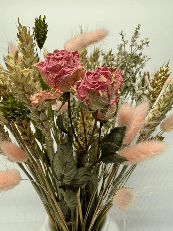 Close-up of dried pink roses with bunny tails and wheat grasses in a dried flower arrangement
