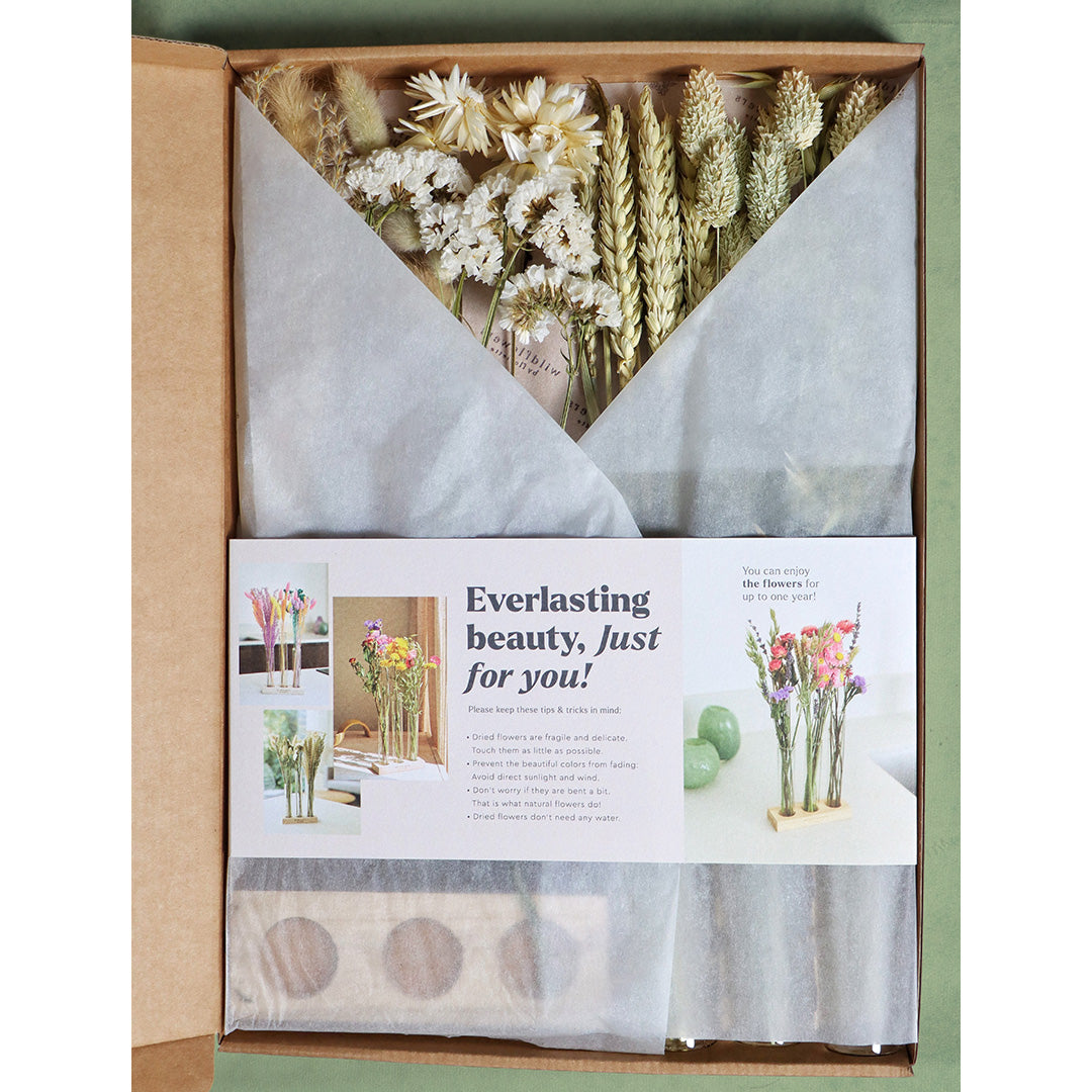 Box of dried flowers with a card inside, featuring text and images of floral arrangements.