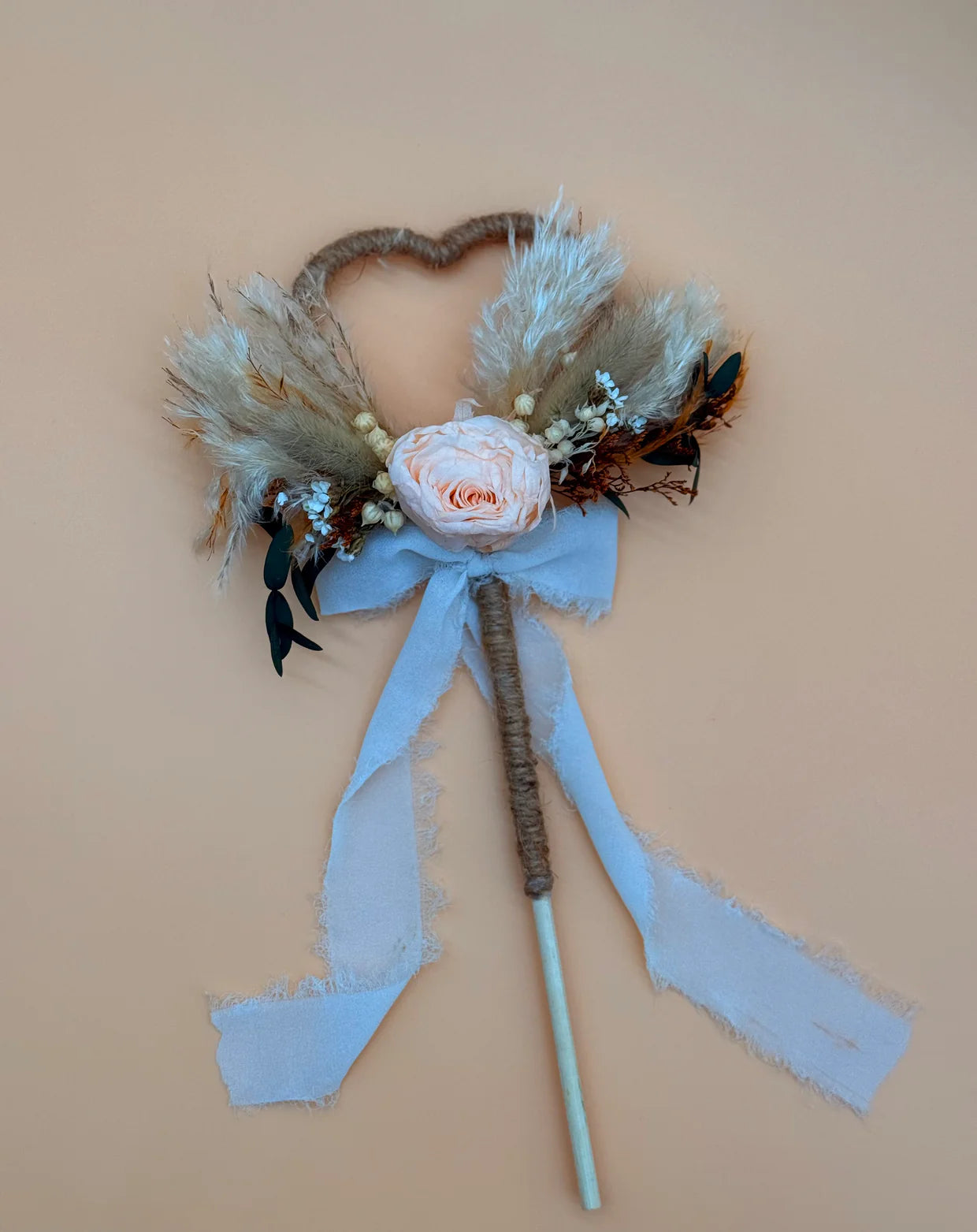 Decorative wand with flowers and ribbons on a beige background
