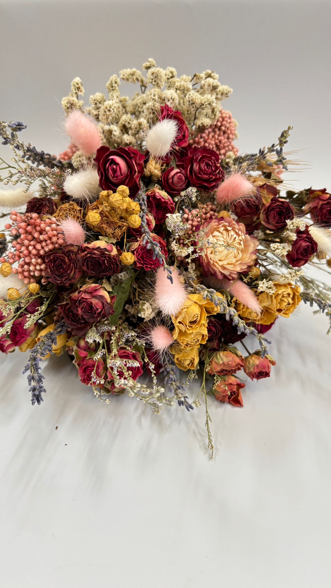 Bouquet of dried flowers with colorful pom-poms on a white background