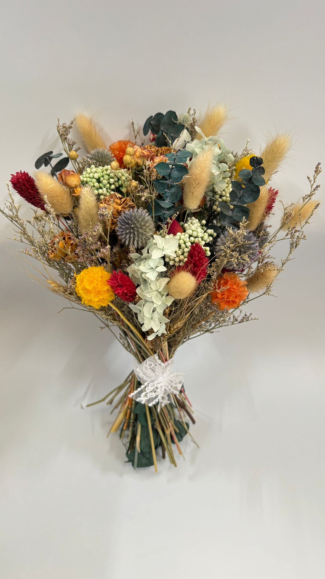 Bouquet of dried flowers with colorful elements on a light gray background