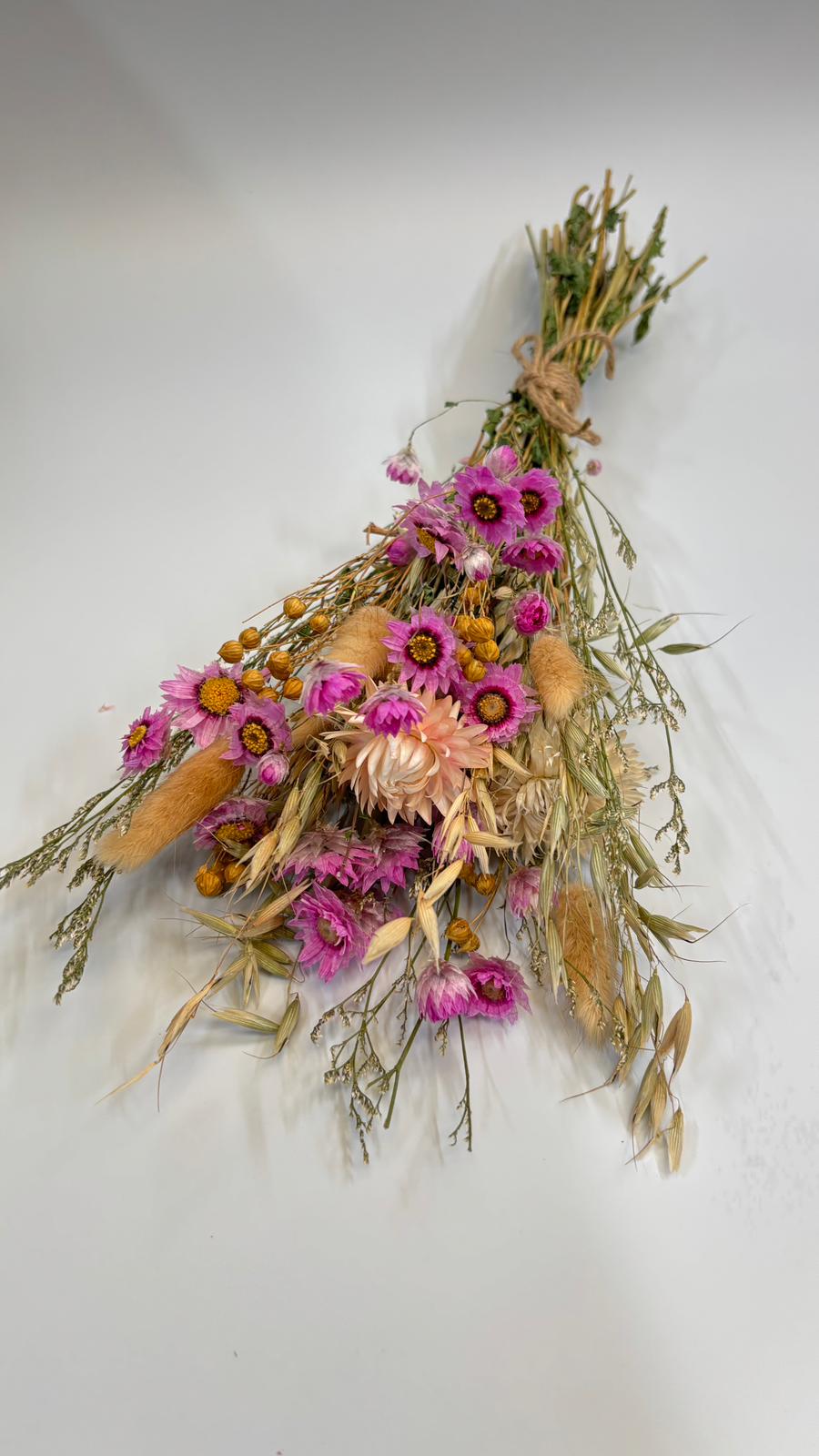 Dried floral arrangement with pink and orange flowers on a white background