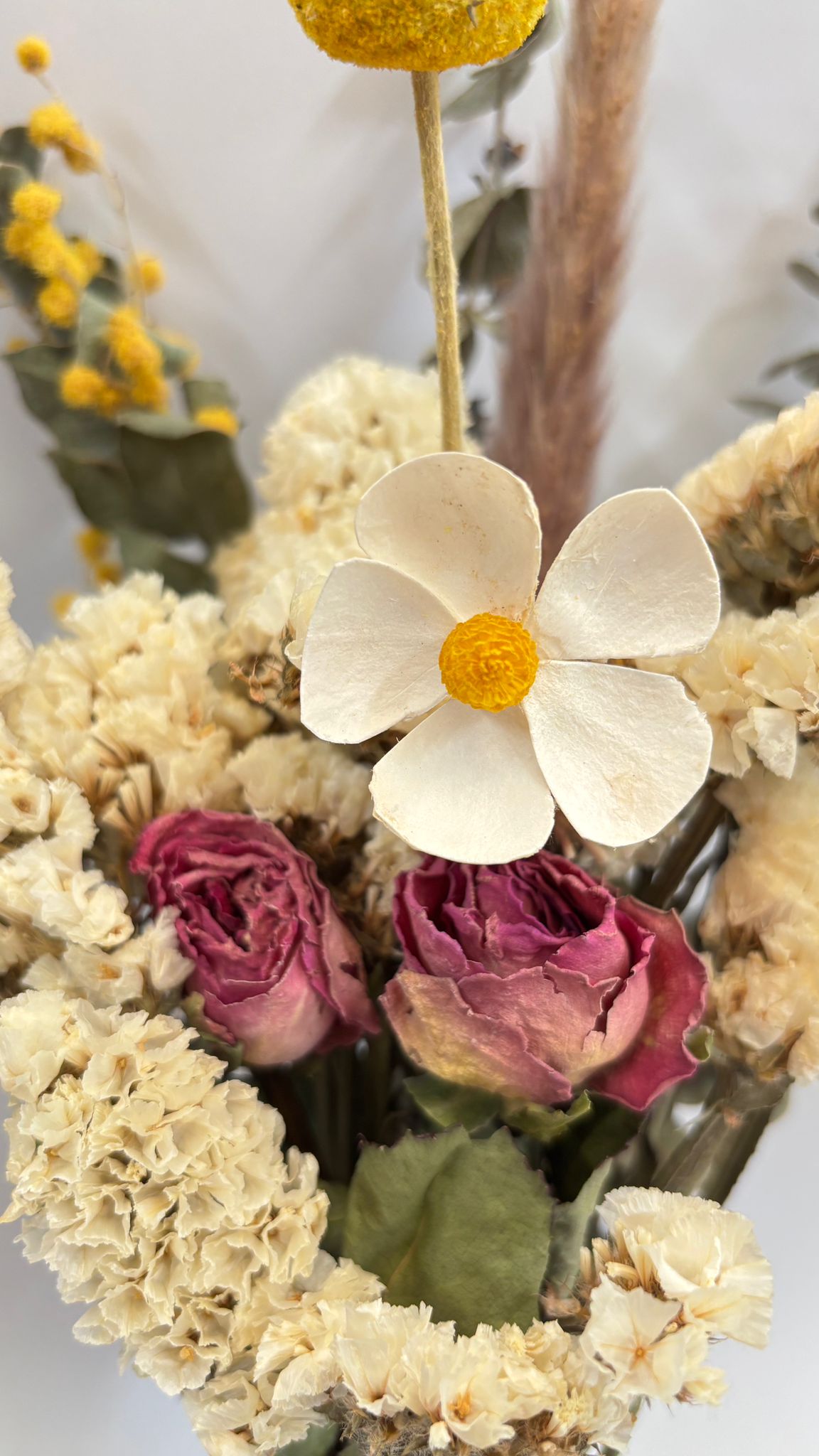 Close-up of dried flowers with a prominent white flower and pink buds.
