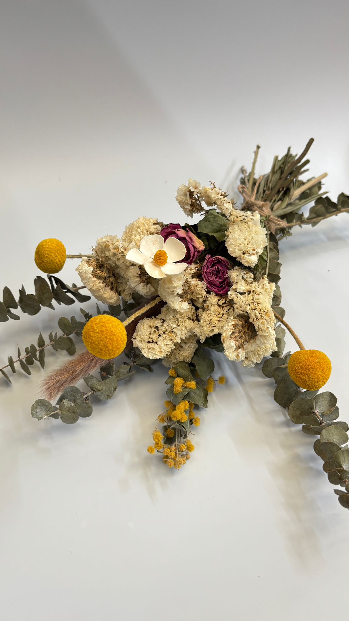 Dried flowers and greenery on a white surface
