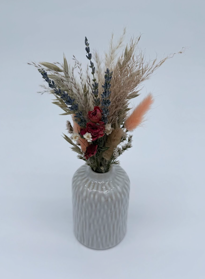 White textured vase with dried flowers on a light surface