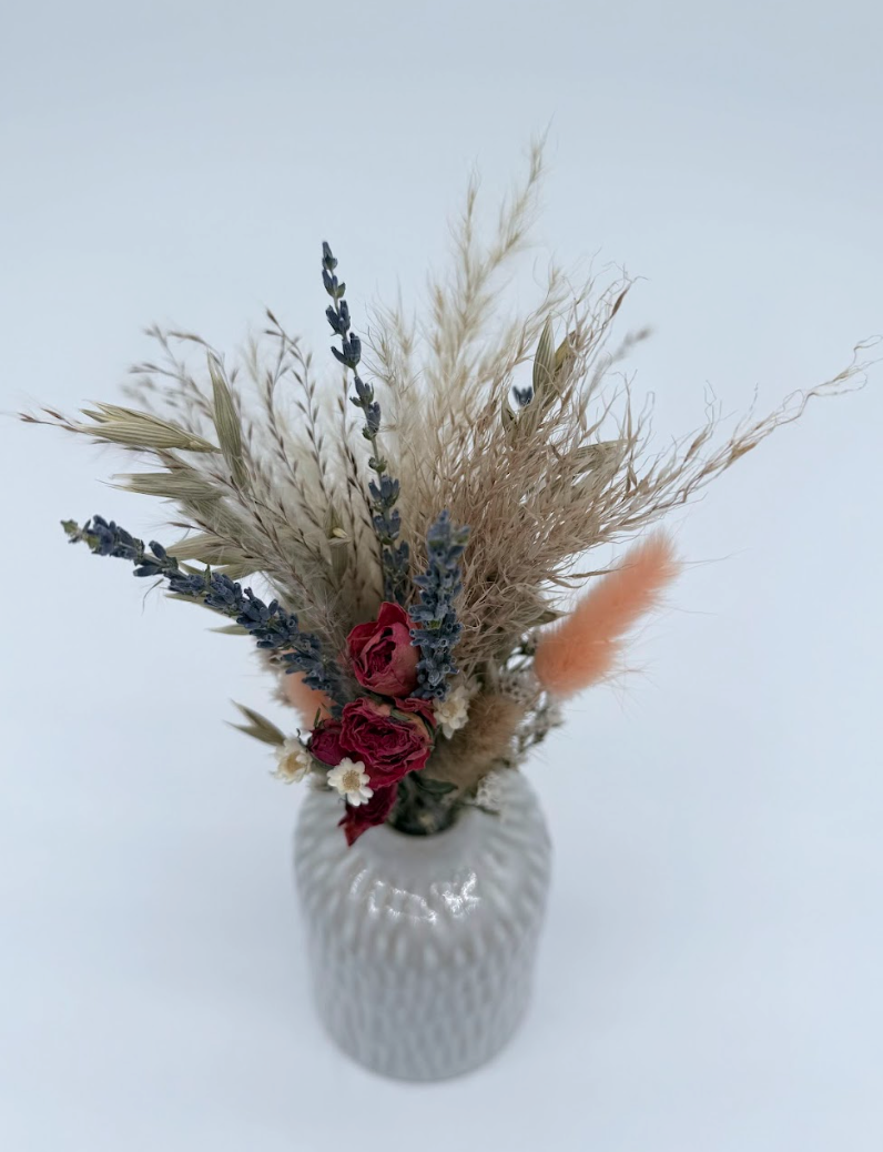 Decorative vase with dried flowers and herbs on a light blue background