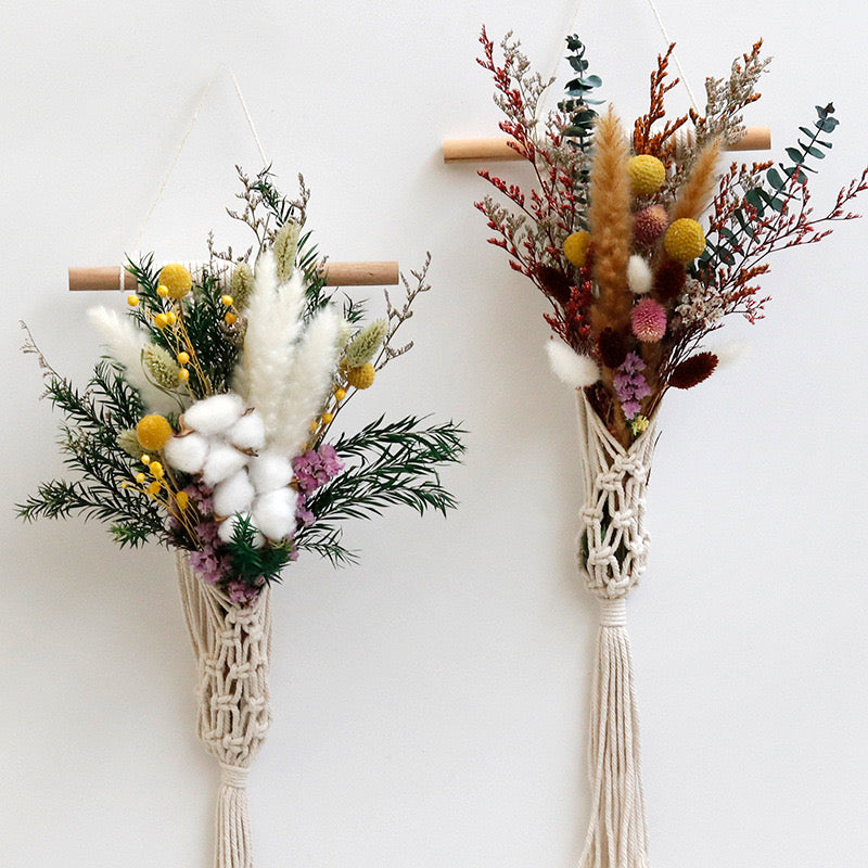 Two macrame plant hangers with dried flowers and plants on a white background