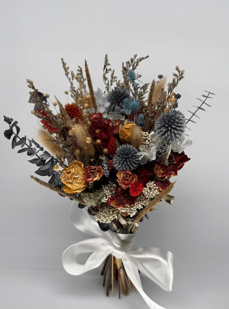 Bouquet of dried flowers with a white ribbon on a light gray background
