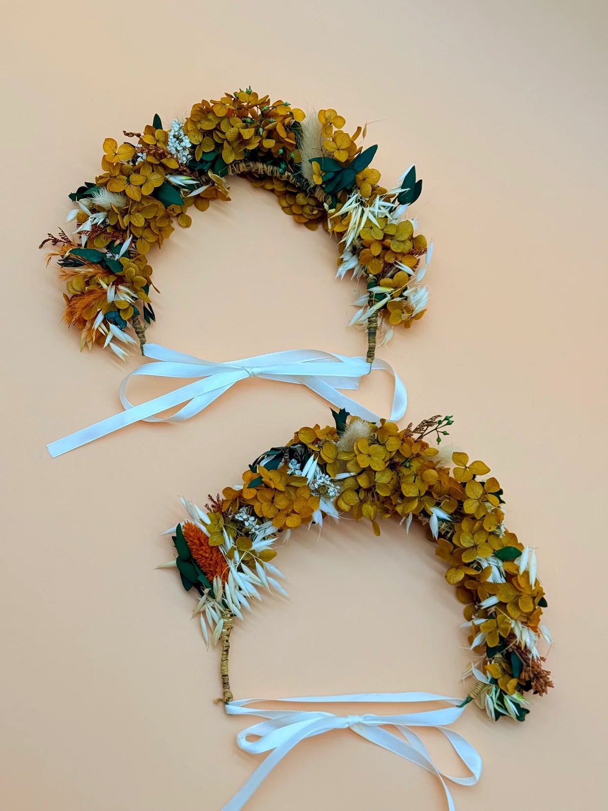 Floral headband with yellow and green flowers and a blue ribbon on a beige background