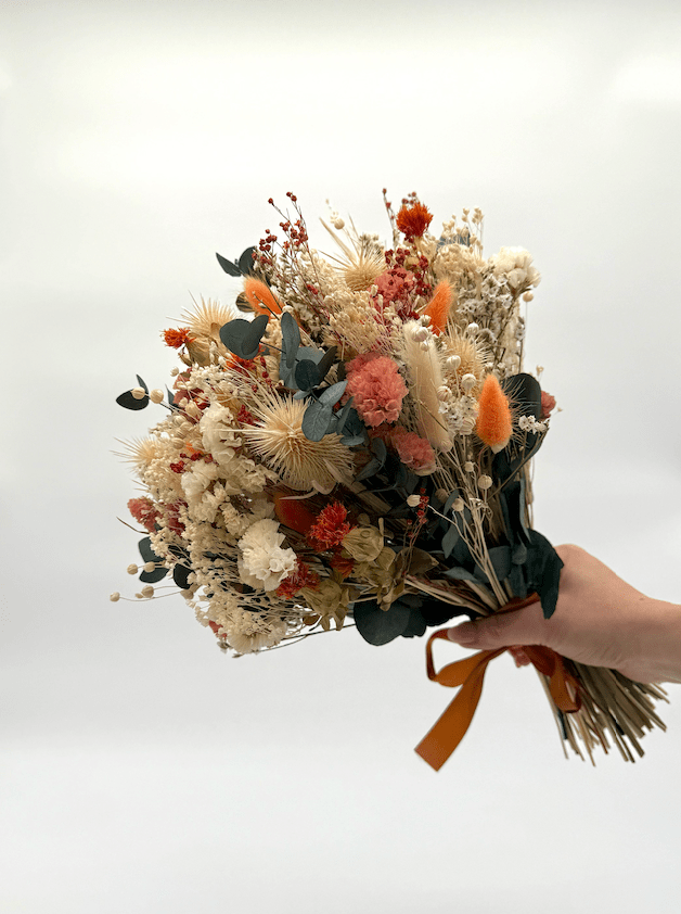 Bouquet of dried flowers held by a hand on a white background