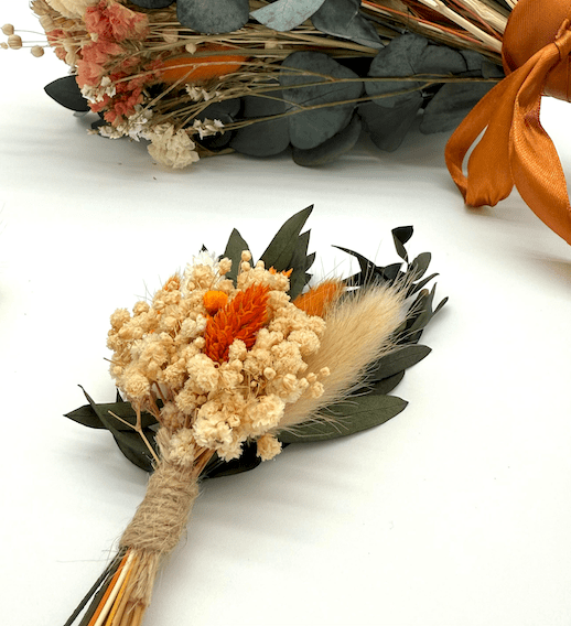 Dried flower arrangement with orange and beige flowers on a white background