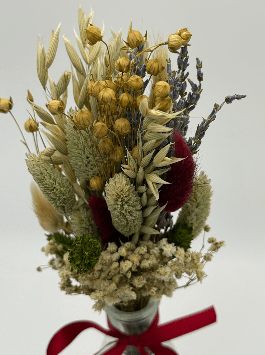 Bouquet of dried flowers with a red ribbon on a light gray background